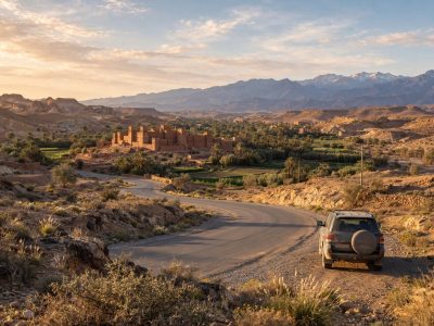 Travelers discussing an Excursion From Ouarzazate beside a kasbah road at golden hour