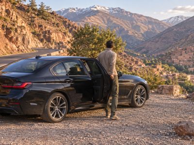 Private Morocco Driver waiting beside a comfortable car on a scenic mountain road